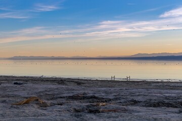 Sunset at the Salton Sea. The calm water reflects the pastel sky, with mountains in the distance....