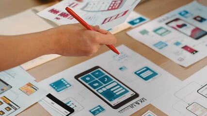 Hand focus of startup company employee present user interface prototype for mobile application to smart manager in office workspace. UX UI designer explain function of icon design on paper. Synergic