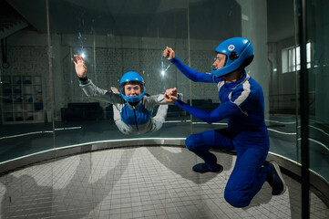 A male instructor teaches a woman how to fly in a wind tunnel. Free fall simulator.
