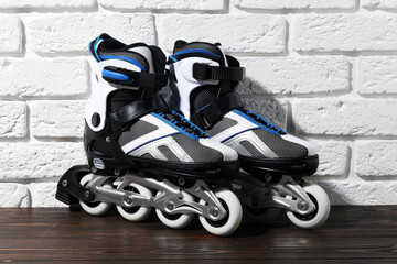 Pair of roller skates on wooden table near white brick wall