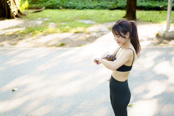 Asian woman using smartwatch or tracker to track her workout progress.