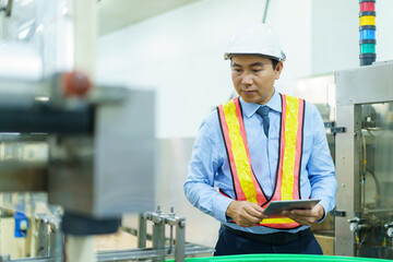Asian engineer manager checks the machine and system in facility.