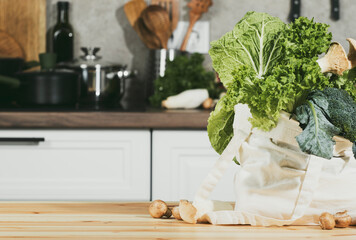 Fresh organic vegetables and herbs in eco-friendly bag on kitchen table for healthy cooking from farmer's market