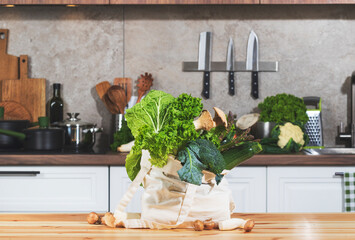 Fresh vegetables and herbs in an eco-friendly bag on a kitchen table ready for healthy meal...