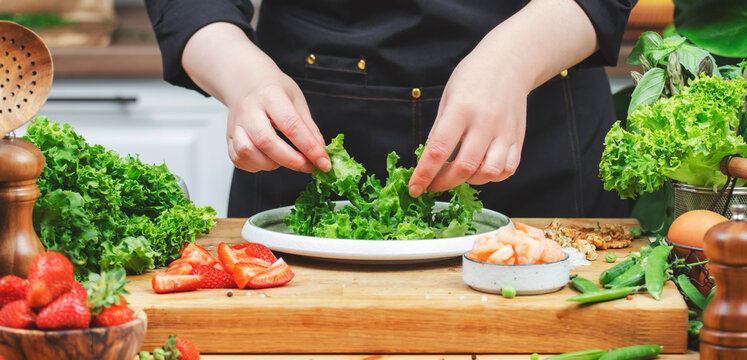 woman chef prepares vibrant lettuce salad with fresh greens and fruits in a modern kitchen, showcasing healthy cooking habits. - Powered by Adobe