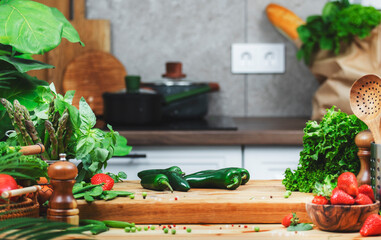 Fresh green jalapeno pepper and vegetables arranged on wooden cutting board in a sunny kitchen for...