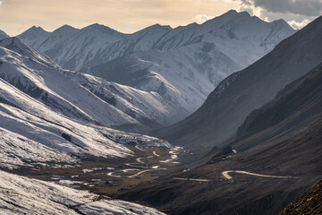 Winding Stream in a Snow-Covered Mountain Valley at Sunset