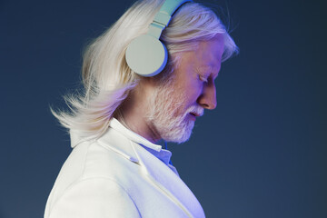 Elderly man with headphones enjoying music, close up profile view, soft blue background, highlights his serene expression and silver hair, showcasing the connection between music and relaxation