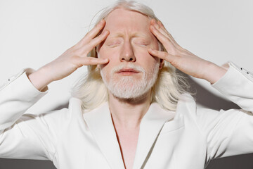 Portrait of a middle aged man with white hair in a white suit, expressing deep contemplation or...