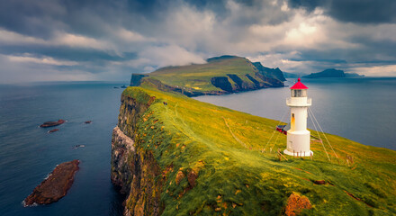 Spectacular summer sunset on Mykines island with old lighthouse. Gloomy evenning view of Faroe Islands, Denmark, Europe. Exciting seascape of Atlantic ocean. Traveling concept background.