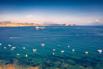 A lots of small fishing boats and big industrial ship with crane on background. Amazing morning view bay near Naples port, Italy, Europe. Wonderful seascape of Mediterranean sea.