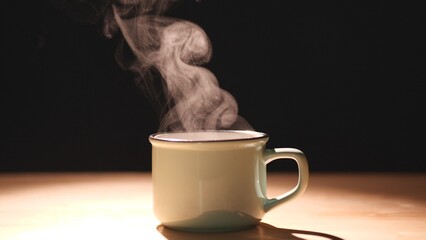 Coffee. Close-up a cup and mug of coffee on an antique table with gorgeous steam vapor spinning...