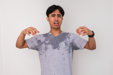 Portrait of a young Asian man sweating and showing a disgusted face expression from his own body...