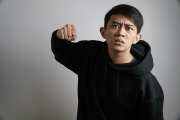 Angry Young Asian Man Threatening with Fist