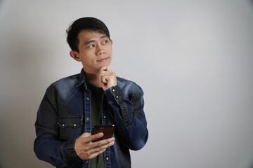 Thoughtful Asian Man with Smartphone Looking Up