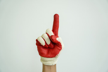 Hand in a red and white work glove pointing index finger upwards, symbolizing number one, success,...