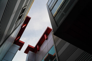 Striking low-angle view of modern building facades with sharp angles and contrasting red and grey...