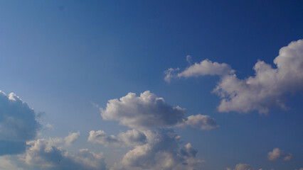 Serene view of a bright blue sky with fluffy white cumulus clouds on a clear sunny day, a natural atmospheric background