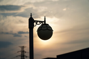 Ornate Street Lamp Silhouetted Against Sunset Sky, A dramatic silhouette of a classic street light at dusk
