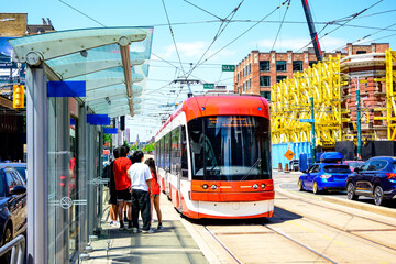 Public transport: a group of young people wait for an arriving street car at a stop on the...