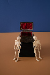 Open old golden coffin standing on a black box guarded by two Halloween skeletons
