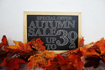 Autumn Sale 30% off text with maple leaf decoration on wooden background
