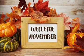 Welcome November text with maple leaf decoration on wooden background