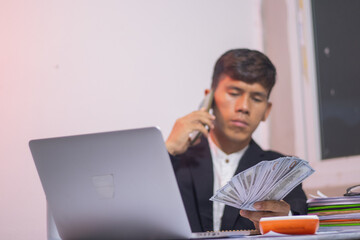 Asian businessman sitting at desk, looking thoughtful and stressed. There are many financial...