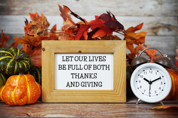 Let Our Lives Be Full Of Thanks And Giving text with maple leaf decoration on wooden background