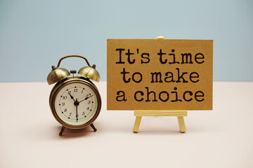 It's time to make a choice text with easel and alarm clock on blue and pink background