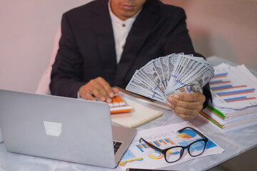 Asian businessman sitting at desk, looking thoughtful and stressed. There are many financial...