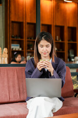 A woman in a cafe enjoying a cup of coffee while working on her laptop, surrounded by a warm wooden...