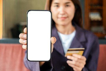 Close-up of a woman displaying a smartphone with a blank screen and holding a credit card, ideal for online shopping themes.