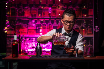 Bartender is pouring whiskey into a glass a customer's glass.