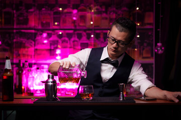 Bartender is pouring whiskey into a glass a customer's glass.