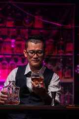 Bartender is pouring whiskey into a glass a customer's glass.	