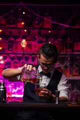 Bartender is pouring whiskey into a glass a customer's glass.	
