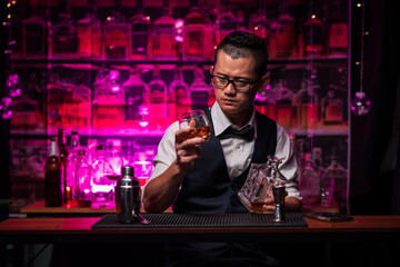 Bartender is pouring whiskey into a glass a customer's glass.