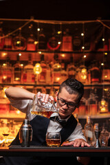 Bartender is pouring whiskey into a glass a customer's glass.
