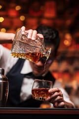 Bartender is pouring whiskey into a glass a customer's glass.	
