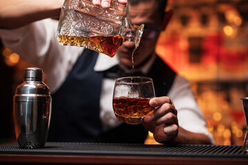 Bartender is pouring whiskey into a glass a customer's glass.