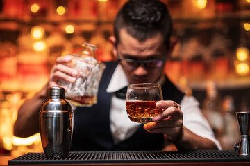 Bartender is pouring whiskey into a glass a customer's glass.