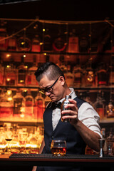 Bartender is pouring whiskey into a glass a customer's glass.