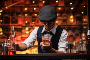 Bartender is pouring whiskey into a glass a customer's glass.