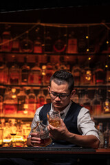 Bartender is pouring whiskey into a glass a customer's glass.