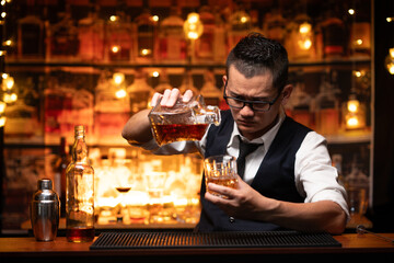 Bartender is pouring whiskey into a glass a customer's glass.	
