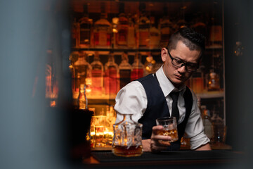 Handsome businessman or young man sits, drinks whiskey, looks stressed and sad.