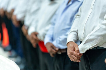 Group of men in blue vests standing together. group of people holding hands. Large group of waiters...