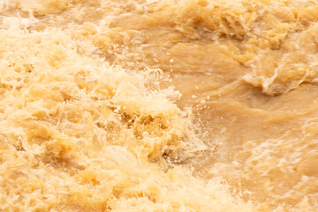 Brown water with ripples on the surface. Defocus blurred transparent brown colored clear calm water surface texture with splashes and bubbles. Water waves with shining pattern texture background.