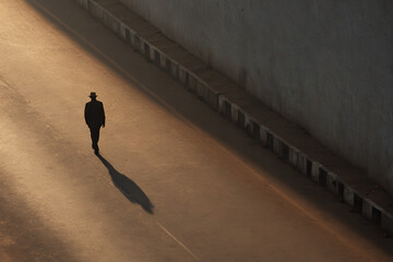 minimalist studio photograph featuring single person on urban highway in india long shadows cast by setting sun